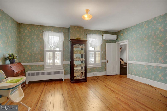 sitting room featuring radiator heating unit, a wall mounted AC, and light wood-type flooring