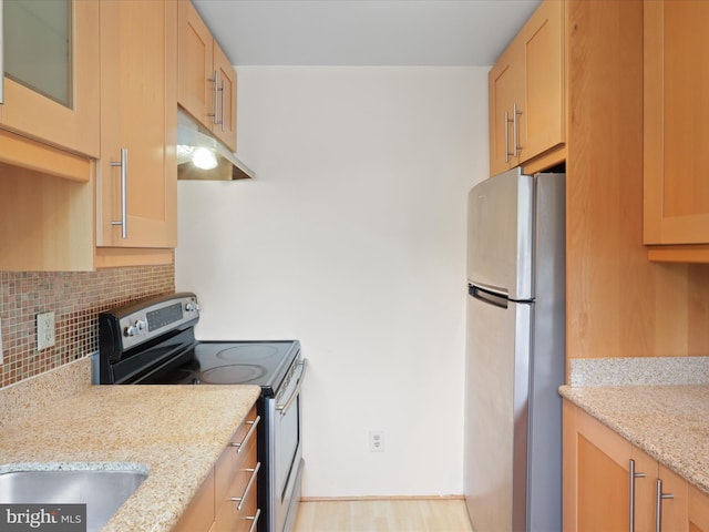 kitchen featuring light stone counters, stainless steel appliances, light brown cabinetry, and backsplash