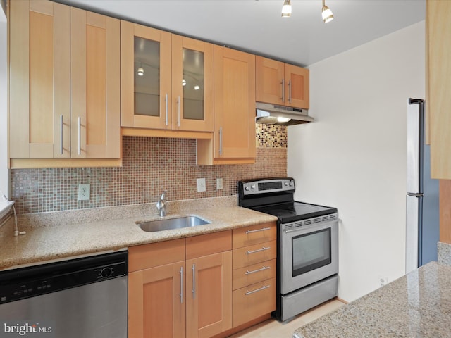 kitchen featuring light brown cabinetry, sink, backsplash, light stone counters, and stainless steel appliances