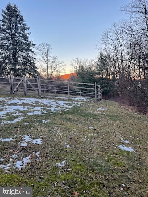 yard at dusk featuring a rural view