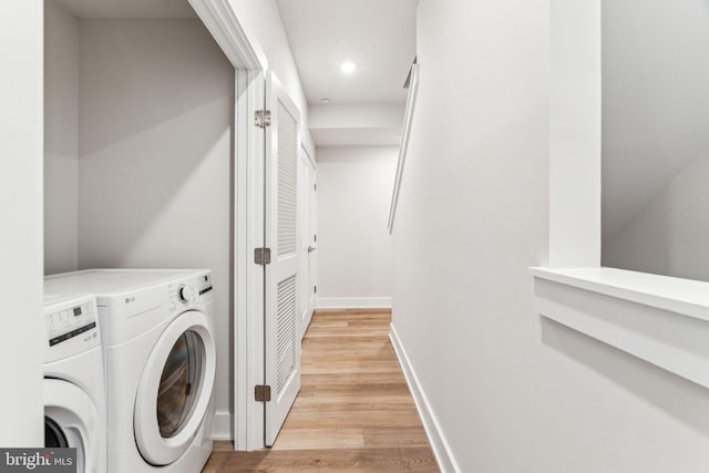 laundry area featuring washing machine and dryer and light hardwood / wood-style floors