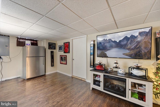 bar with dark wood-type flooring, a drop ceiling, stainless steel fridge, and electric panel