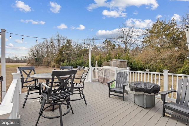 wooden deck with a storage shed and a grill