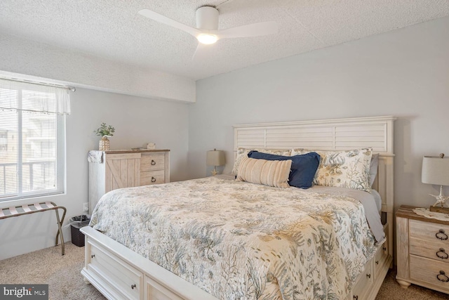 bedroom with ceiling fan, light colored carpet, and a textured ceiling