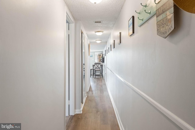 hall with hardwood / wood-style flooring and a textured ceiling