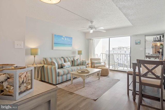 living room featuring hardwood / wood-style floors, a textured ceiling, and ceiling fan