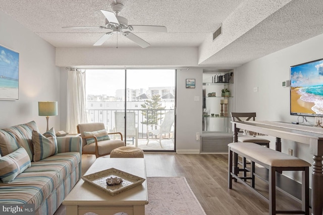 living room featuring ceiling fan, a textured ceiling, and light wood-type flooring