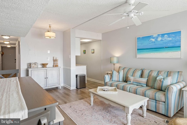 living room with ceiling fan, a textured ceiling, and light hardwood / wood-style floors