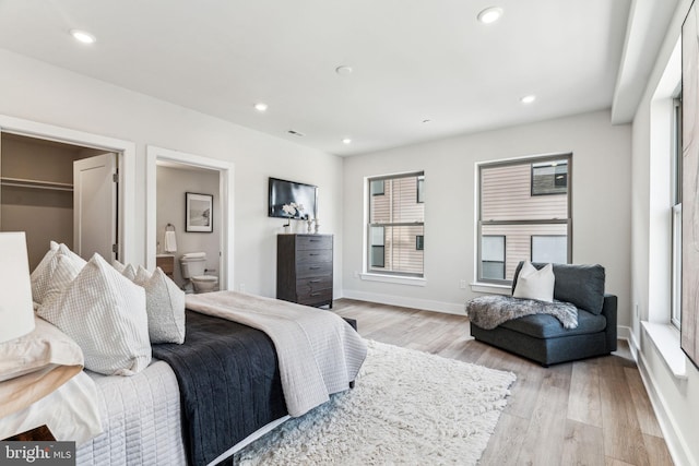 bedroom featuring connected bathroom and light hardwood / wood-style floors