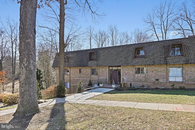 view of front of house featuring a front yard, a shingled roof, mansard roof, and brick siding