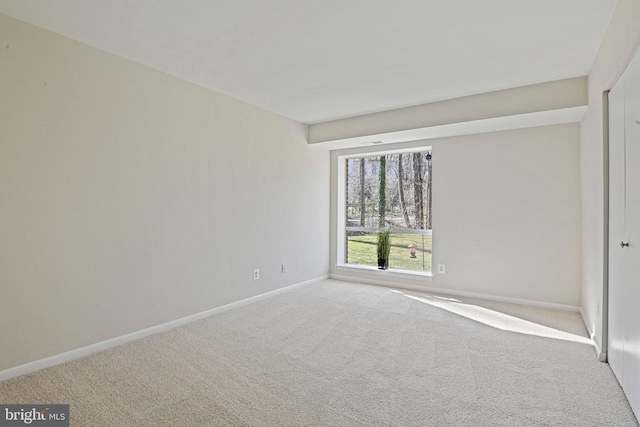 carpeted empty room featuring baseboards