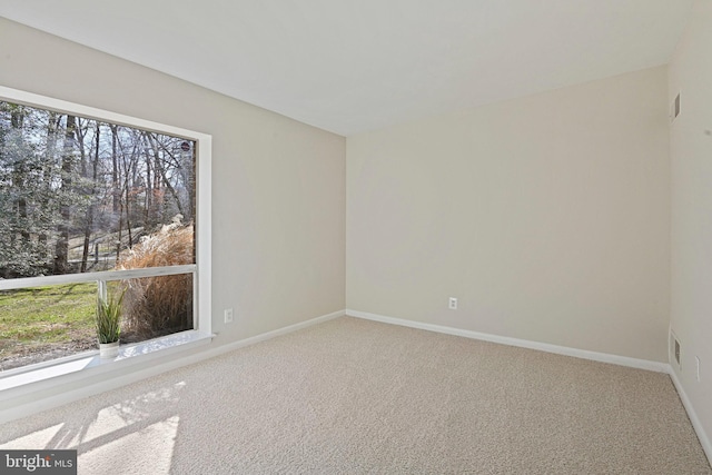 carpeted empty room featuring plenty of natural light and baseboards