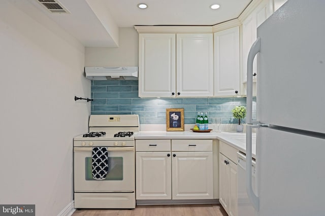 kitchen featuring white appliances, visible vents, tasteful backsplash, and under cabinet range hood