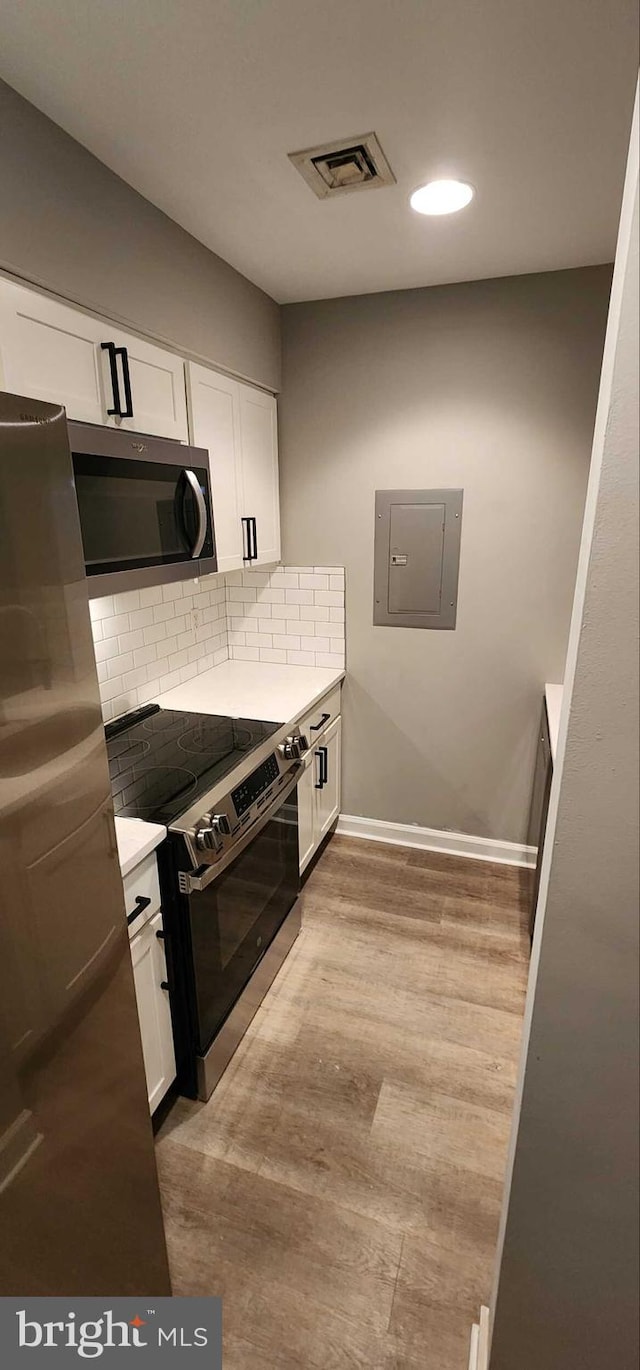 kitchen featuring white cabinets, appliances with stainless steel finishes, electric panel, and backsplash