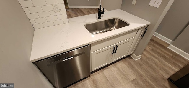 room details featuring sink, stainless steel dishwasher, white cabinets, and light hardwood / wood-style flooring