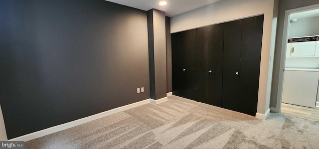 unfurnished bedroom with light carpet, a closet, and stacked washing maching and dryer