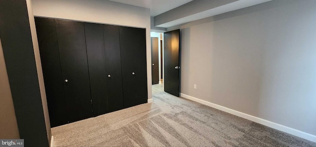 unfurnished bedroom featuring light colored carpet and a closet