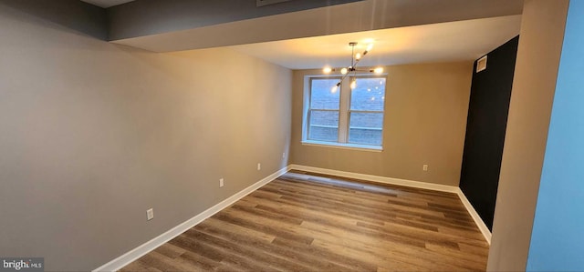 spare room with wood-type flooring and a chandelier