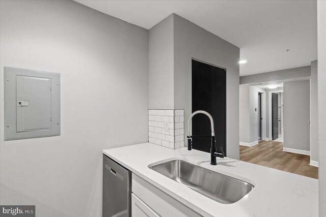 kitchen featuring dishwasher, sink, white cabinets, decorative backsplash, and electric panel