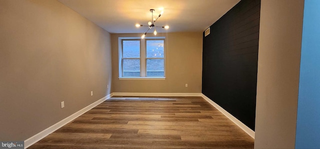 unfurnished room with wood-type flooring and a chandelier