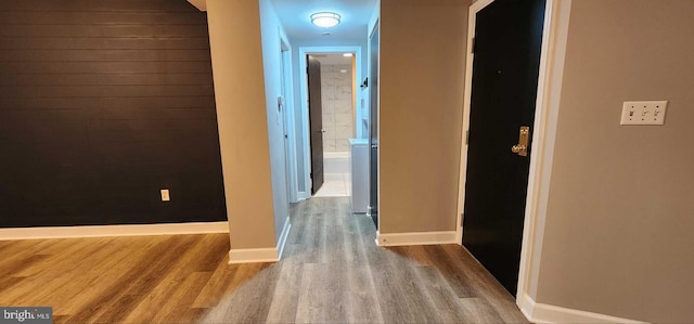 hall featuring wood walls and light hardwood / wood-style flooring