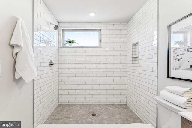 bathroom featuring a tile shower and toilet