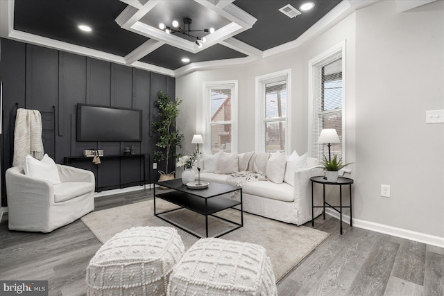 living room featuring coffered ceiling, wood-type flooring, ornamental molding, and a notable chandelier