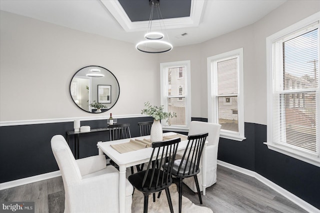 dining space featuring hardwood / wood-style floors, a tray ceiling, and ornamental molding