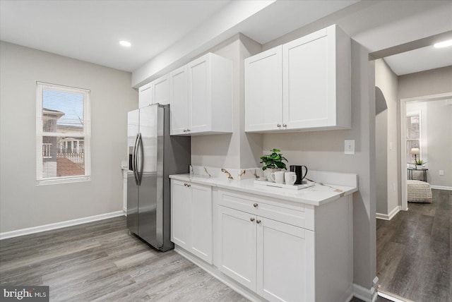 kitchen featuring white cabinetry, light stone counters, and stainless steel fridge