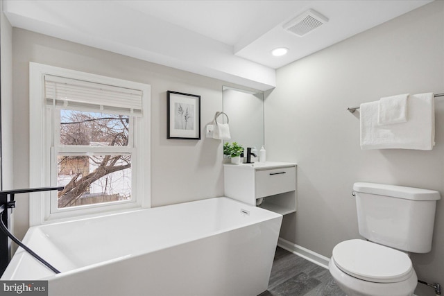 bathroom featuring hardwood / wood-style flooring, vanity, a bathtub, and toilet