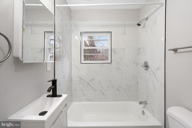 full bathroom featuring vanity, tiled shower / bath combo, and toilet