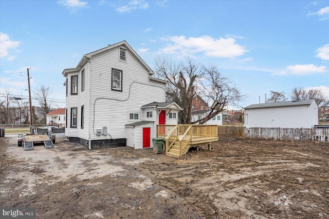 back of house with a wooden deck and a storage unit