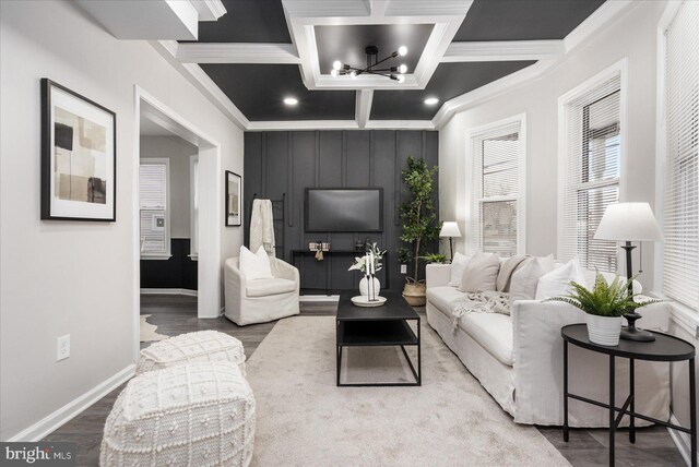 living room with coffered ceiling, a notable chandelier, crown molding, and hardwood / wood-style flooring