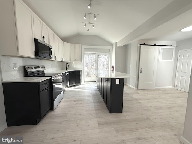 kitchen featuring white cabinetry, appliances with stainless steel finishes, a kitchen island, a barn door, and backsplash