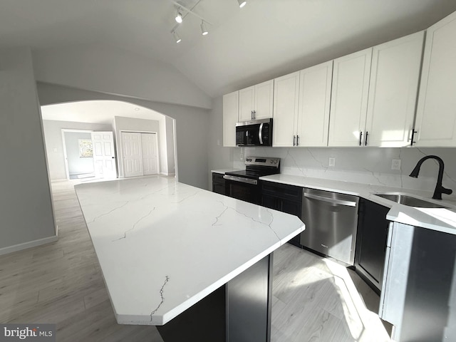 kitchen with sink, white cabinets, a center island, stainless steel appliances, and light stone countertops