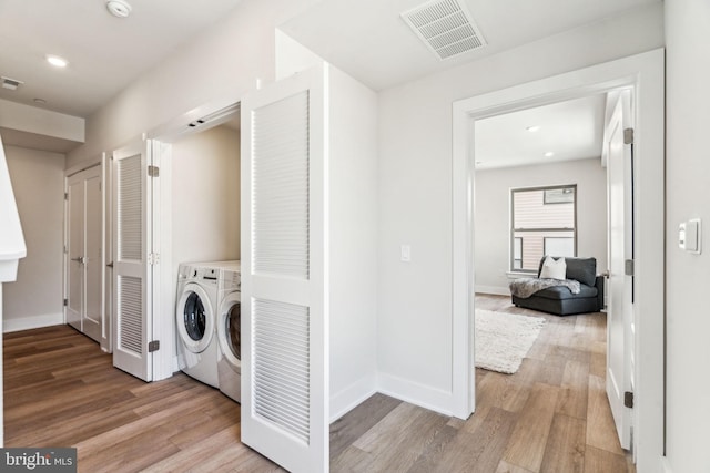 clothes washing area with light hardwood / wood-style flooring and independent washer and dryer