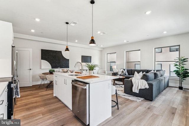 kitchen with pendant lighting, appliances with stainless steel finishes, sink, and white cabinets