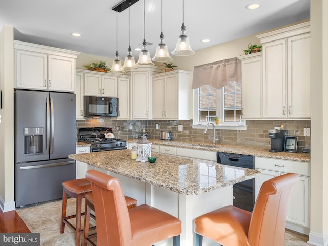 kitchen featuring light stone counters, a center island, hanging light fixtures, a kitchen breakfast bar, and black appliances