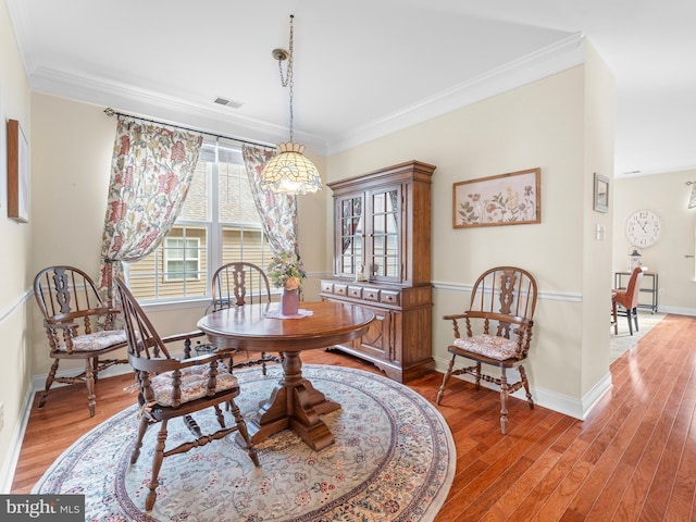 dining area with hardwood / wood-style flooring and ornamental molding