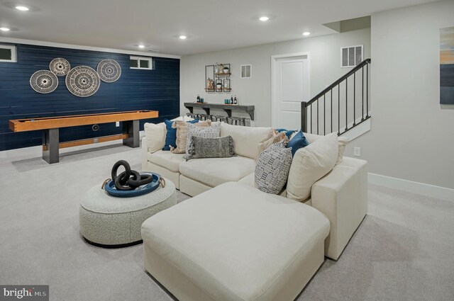 carpeted living room with wood walls