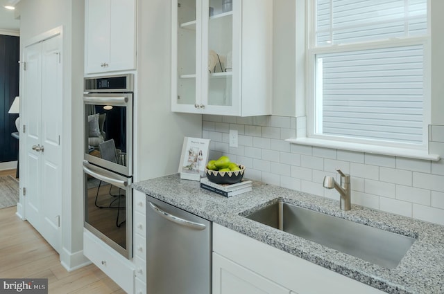 kitchen with white cabinetry, appliances with stainless steel finishes, sink, and light stone counters