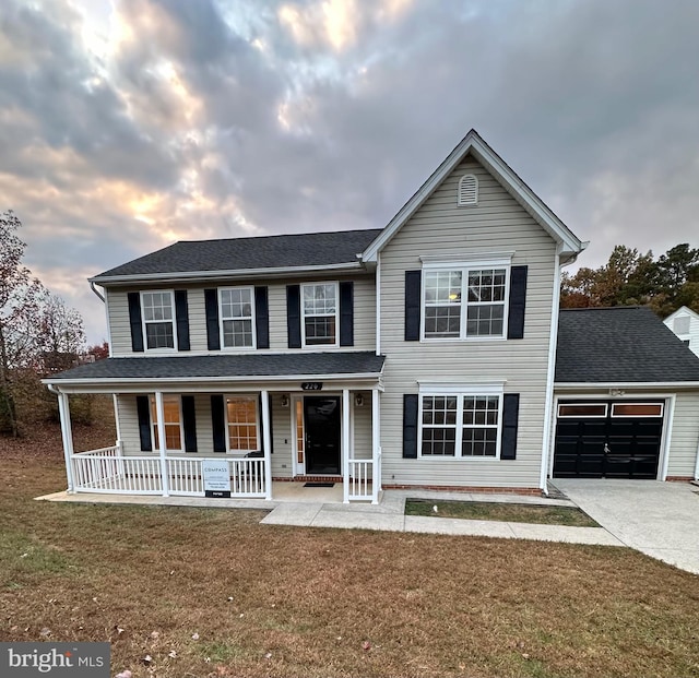 view of front of house featuring a porch, a garage, and a yard