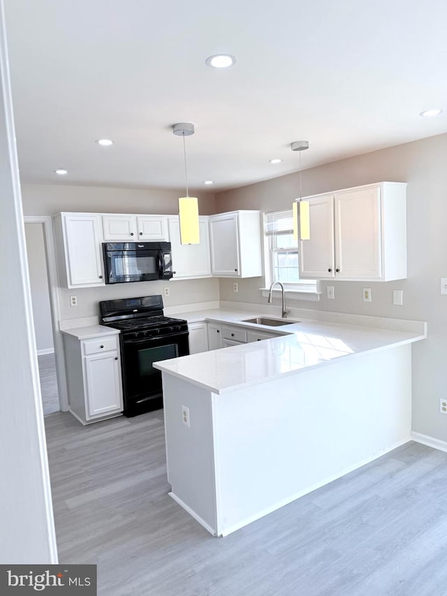 kitchen with sink, decorative light fixtures, kitchen peninsula, and black appliances