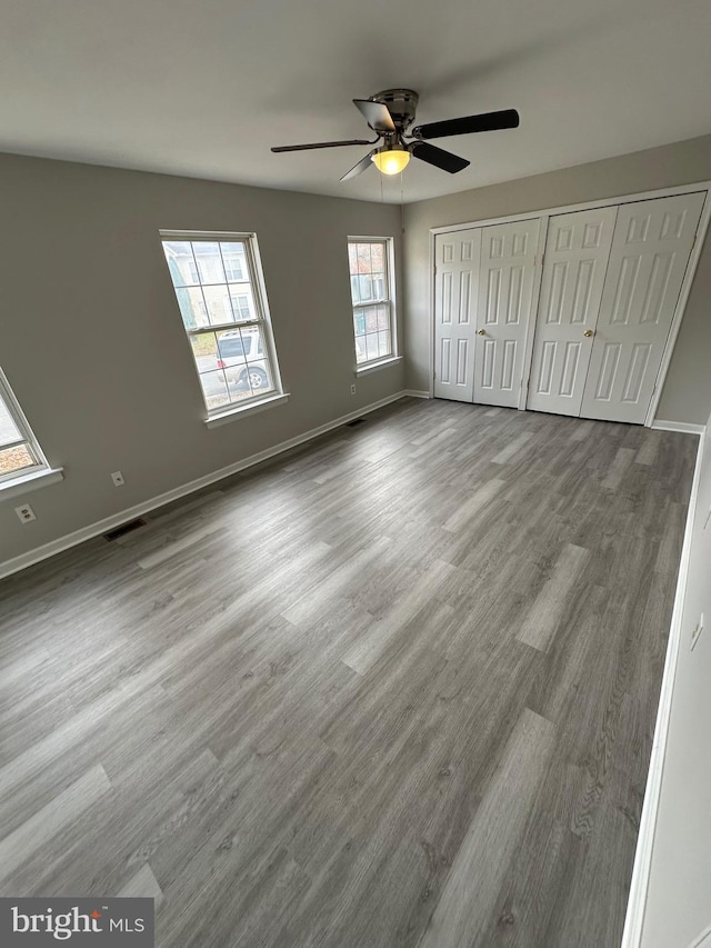 unfurnished bedroom with two closets, wood-type flooring, and ceiling fan