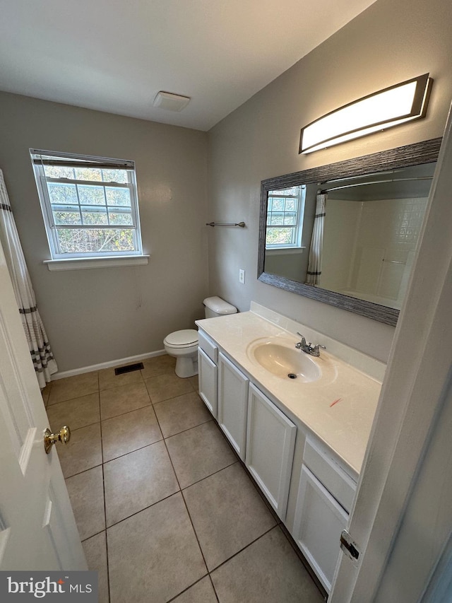 bathroom with a healthy amount of sunlight, tile patterned floors, toilet, and vanity