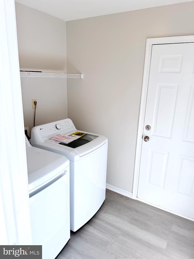 clothes washing area featuring light hardwood / wood-style floors and washing machine and dryer