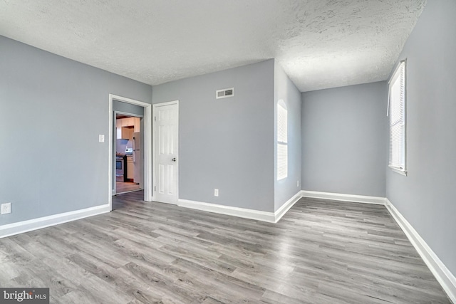 spare room with light hardwood / wood-style floors and a textured ceiling