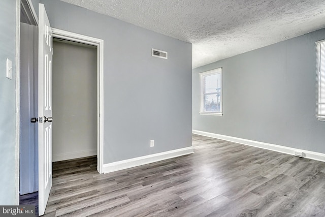 empty room featuring wood-type flooring and a textured ceiling