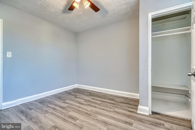 unfurnished bedroom featuring hardwood / wood-style flooring, ceiling fan, a textured ceiling, and a closet