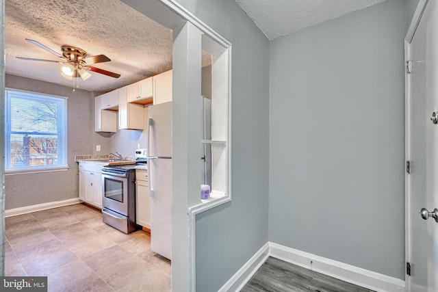 kitchen featuring ceiling fan, white cabinetry, a textured ceiling, stainless steel electric stove, and white fridge